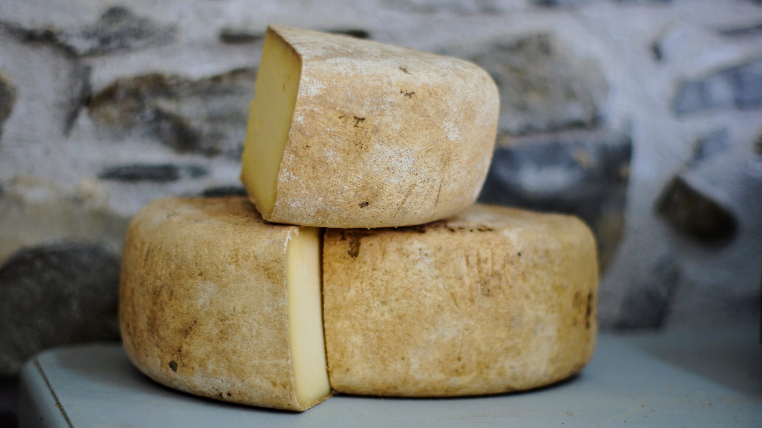 Cut wedges of hard cheese on a blue counter.