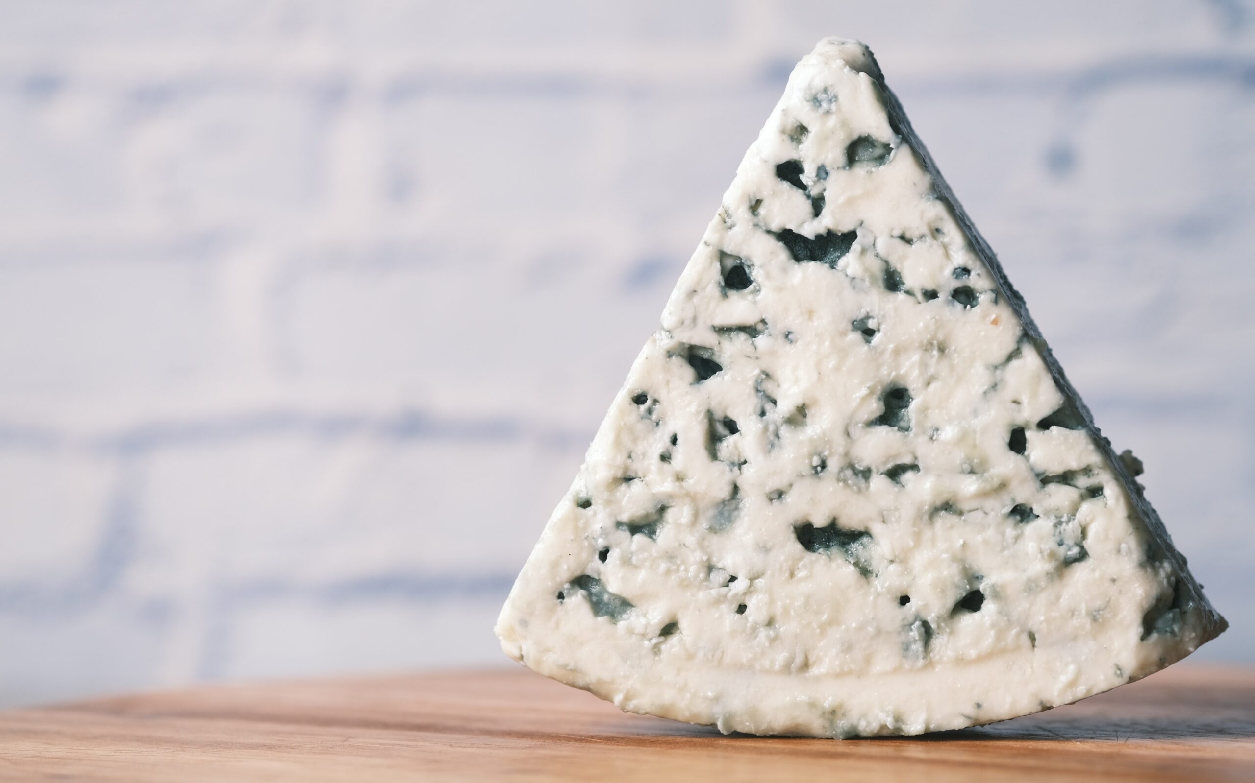 A wedge of blue cheese atop a wood counter.