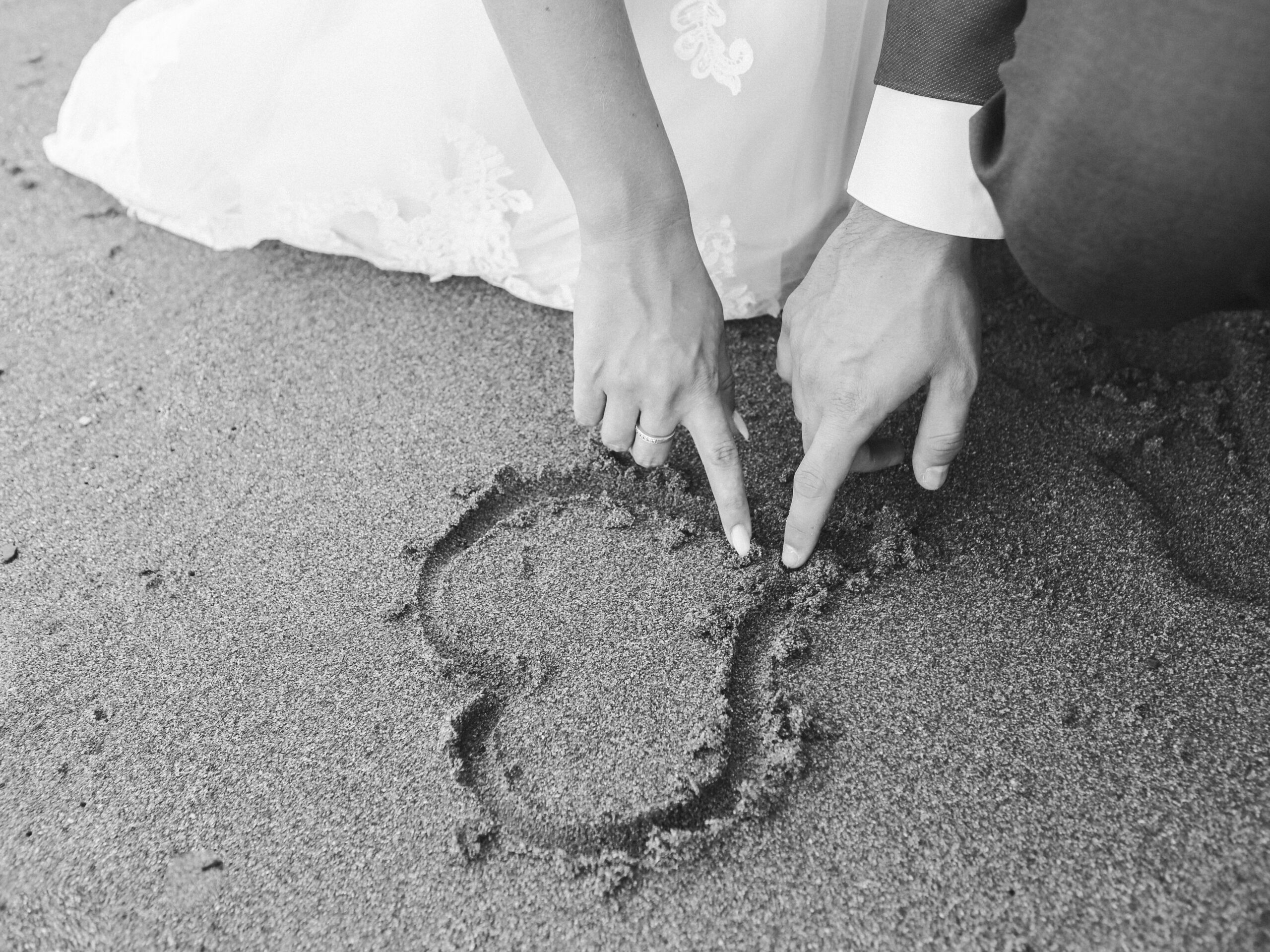 A couple drawing a heart in the sand.