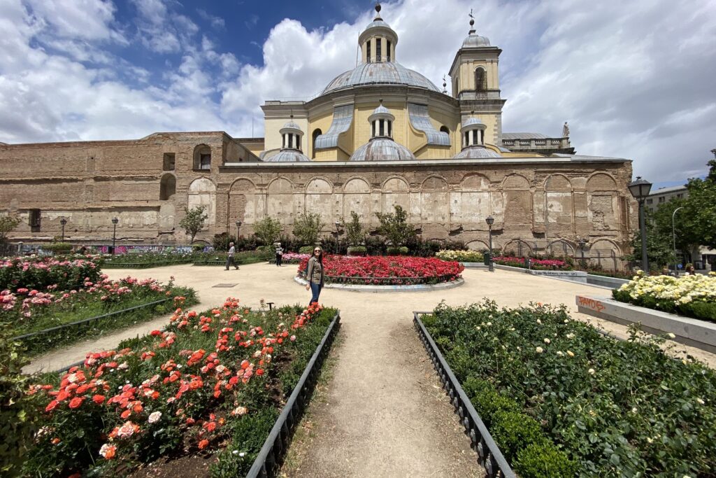 A park surrounded by flowers and a big building.